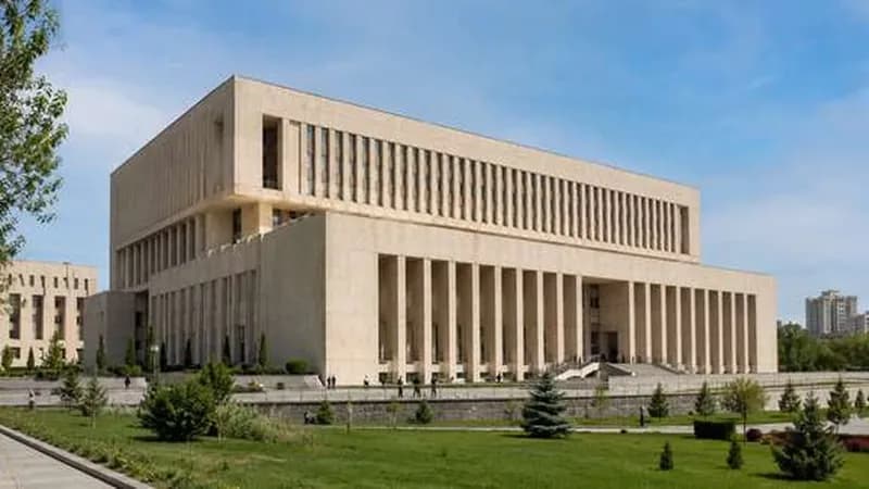 ساختمان اداری دولتی با نمای سنگی روشن و ردیف ستونهای بلند در ورودی، با محوطهٔ چمن مقابل آن
